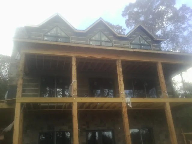 Dormers and porch framing on a large log home under construction — Roof Coating work by our crew in Miramar Beach