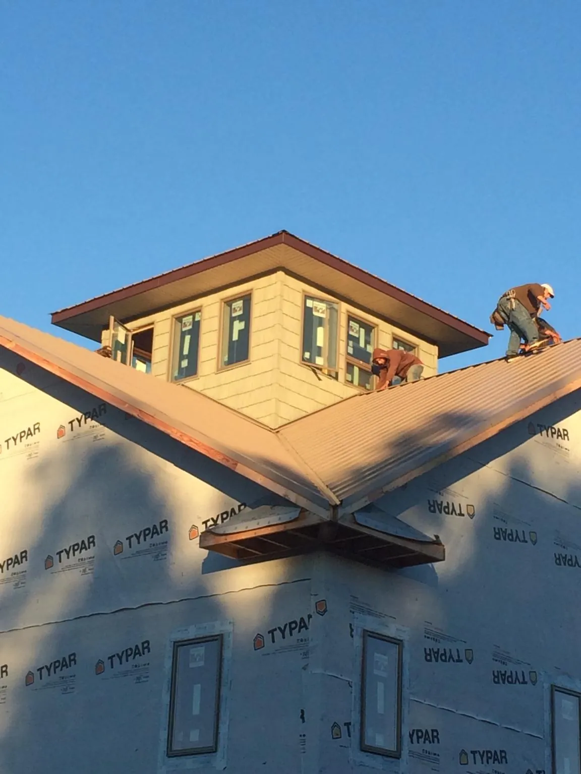 Roofers working around a rooftop cupola on a new metal roof at sunset — Roof Waterproofing in Miramar Beach by Roofing Brothers